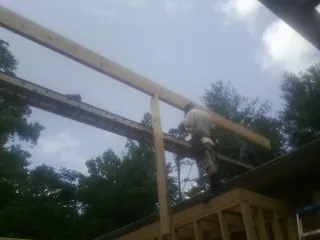 Carpenter setting a ridge beam over a new addition frame — Ice Dam Removal by Roofing Brothers in Fallon