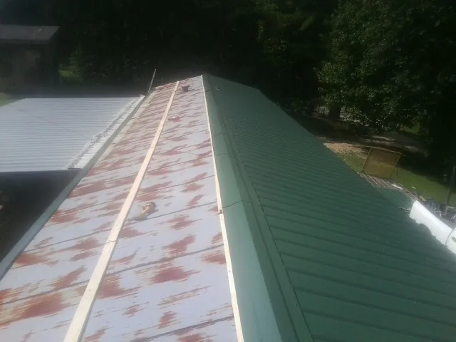 Old rusted panels beside newly installed green metal roofing — Wind Damage Roof Repair by Roofing Brothers in Fallon