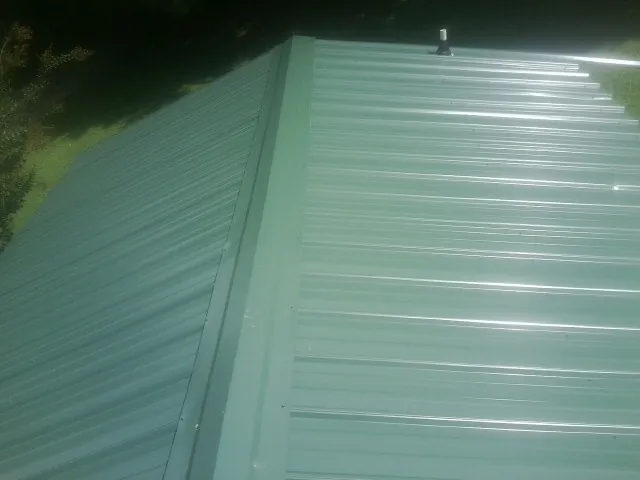 New green metal panels meeting at the ridge of a roof — Flat Roof Repair work by our crew in Fallon