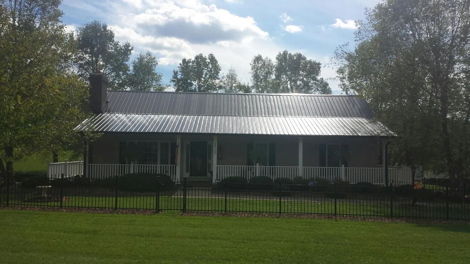 Gray metal roof on a brick ranch with a full width front porch — Gutter Guard Installation work by our crew in Fallon