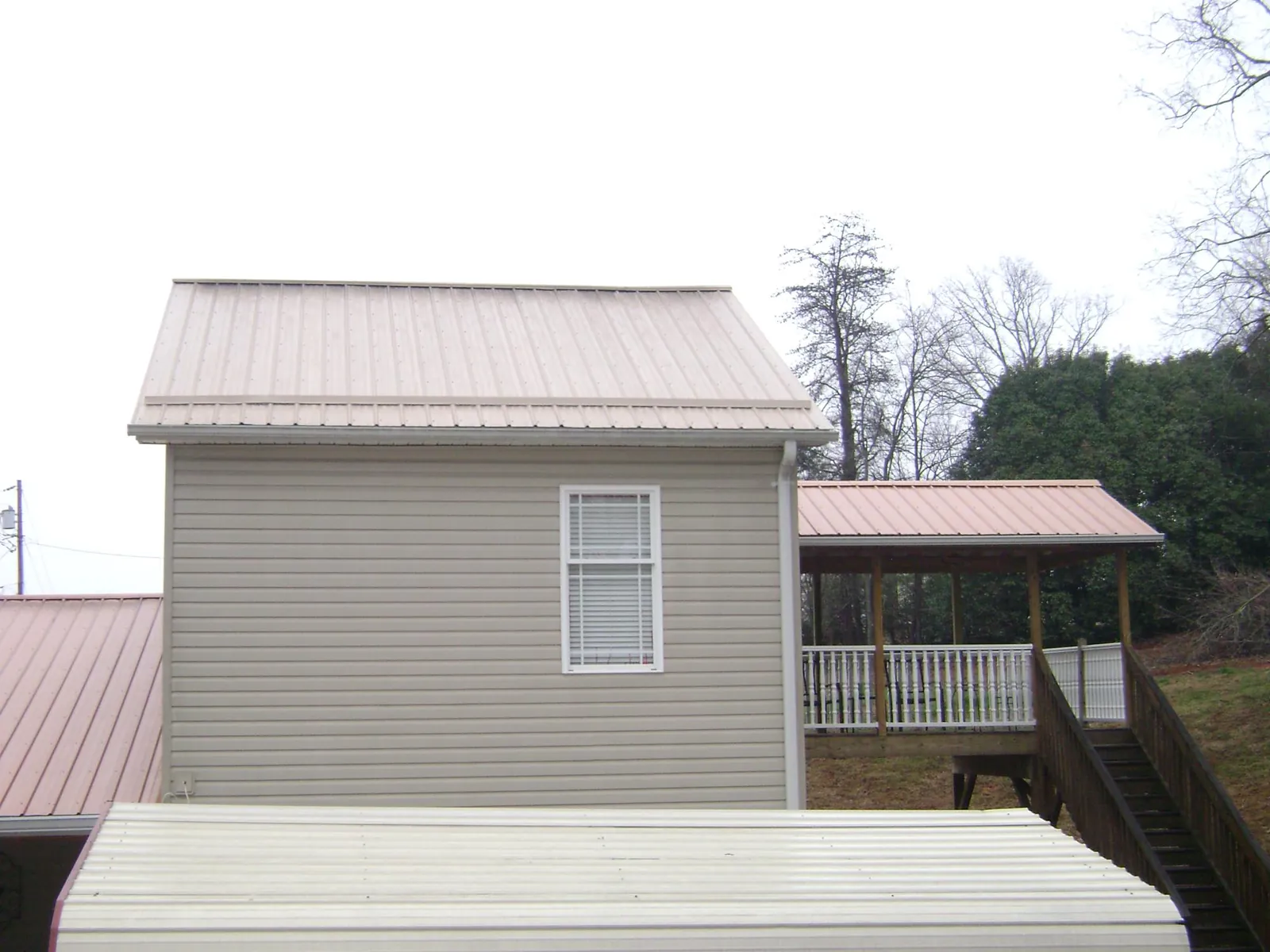 Tan metal roofs on a two story addition and attached porch, from a Roof Replacement job in Fallon