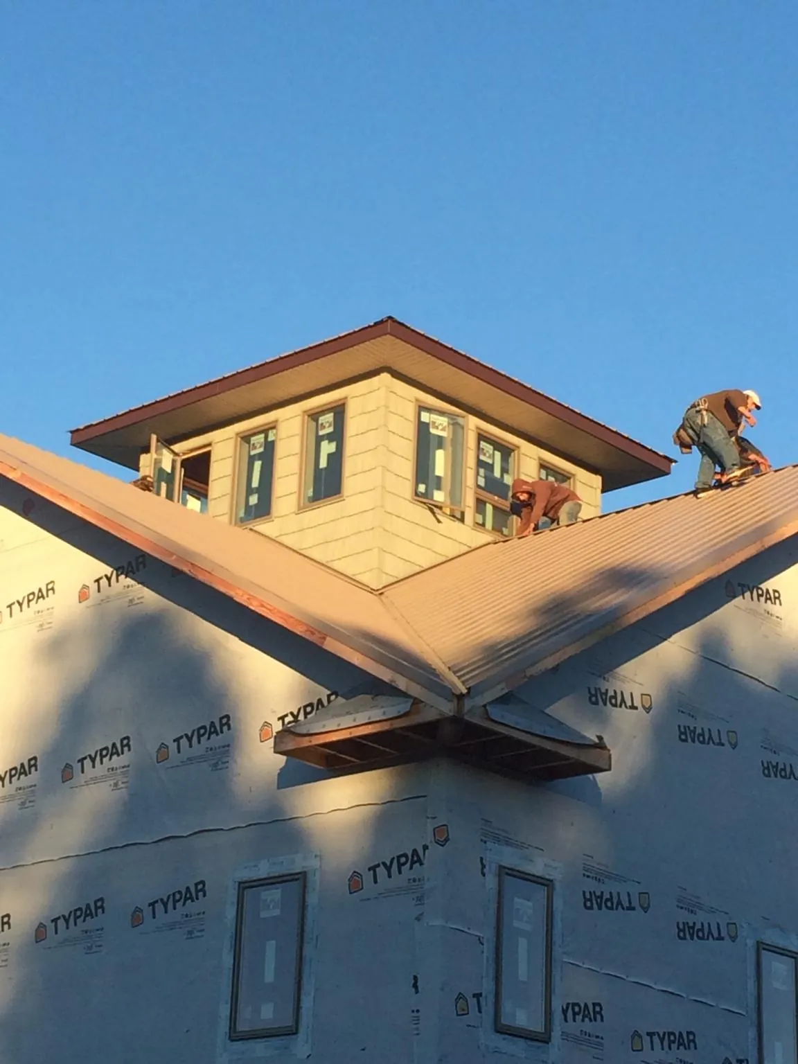 Roofers working around a rooftop cupola on a new metal roof at sunset — Roof Waterproofing in Fallon by Roofing Brothers